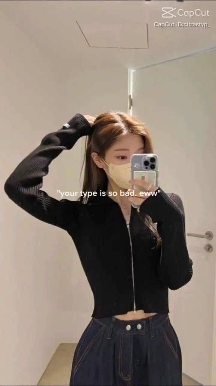 A young woman is taking a mirror selfie in a simple interior space. She is dressed in a fitted black full-sleeve top and a high-waisted dark blue denim skirt. Her left hand is casually lifting her hair up, while her right hand holds a phone with a visible camera in the upper left corner of the device, suggesting it's a modern smartphone. The woman is wearing a yellow face mask, and her face is partially visible in the phone’s reflection. There are logos and text in the top right corner indicating the photo was edited with the 'CapCut' app, and a user handle is mentioned. At the bottom, there's a text overlay that reads, 'your type is so bad. eww. Your Type is Bad CapCut Template